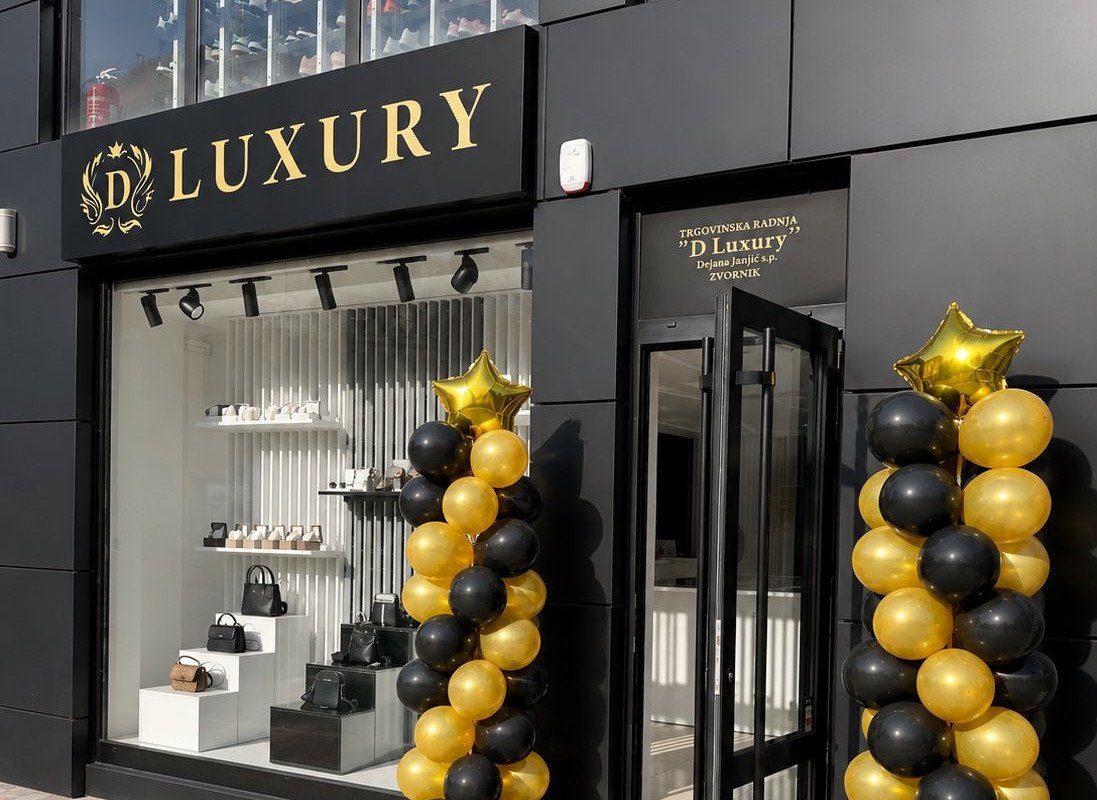 Luxury storefront with gold and black balloon decorations flanking the entrance and gold signage above